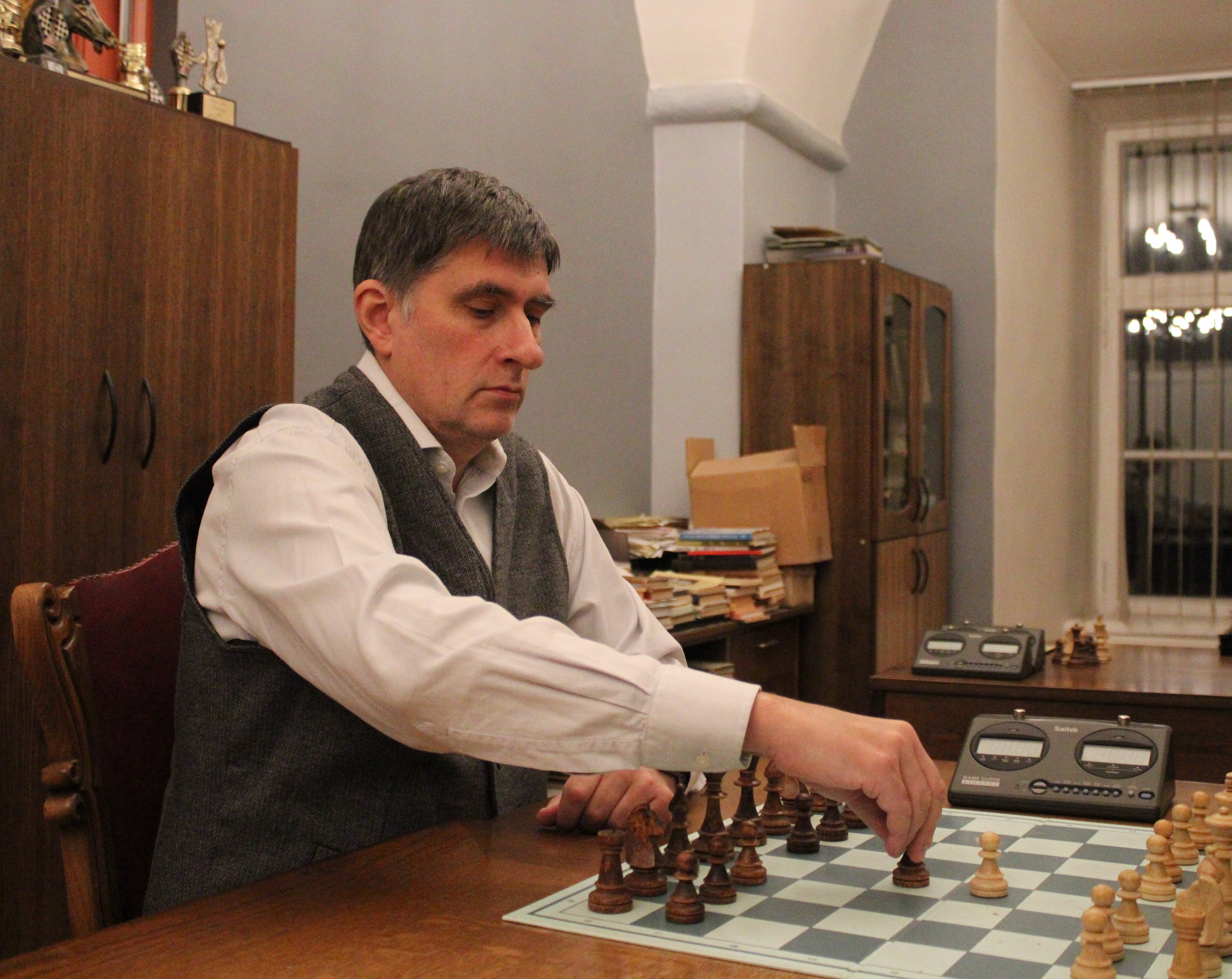 Шахматный тренер спокойно делает ход в шахматном кабинете